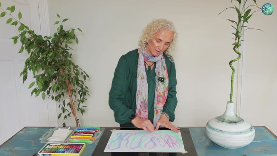 A frame from Week 1: a hand drawing loose, looping lines in purple, blue and green crayon on a large sheet of white paper, a box of pastels beside it.